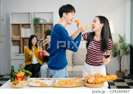 Young Asian friend having, enjoy evening party together at home. Attractive young man and woman having fun, eating food, celebrate at home 134280997