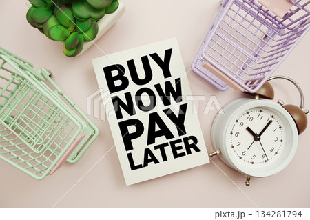 Buy Now Pay Later text with trolley shopping cart and alarm clock on pink background 134281794