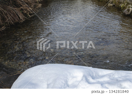 雪の縁と小石が見える清らかな川の流れ 雪の縁と小石が見える清らかな川の流れ 134281840