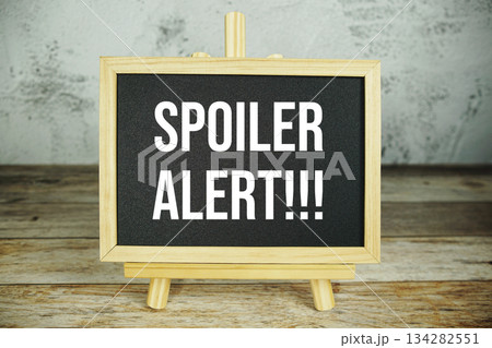 wooden easel displays a blackboard with the bold white text "Spoiler Alert!!!" set against a rustic wooden surface and textured gray wall background wooden easel displays a blackboard with the bold white text "Spoiler Alert!!!" set against a rustic wooden surface and textured gray wall background 134282551
