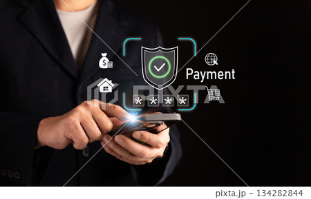 Businessman using smartphone for secure online payment with digital shield icon, representing cybersecurity, mobile banking, e-commerce transaction, data protection, and financial technology 134282844
