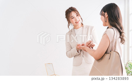 宝石店・アクセサリー・ジュエリーショップ・百貨店で結婚指輪を選ぶ女性と販売員・スタッフ 宝石店・アクセサリー・ジュエリーショップ・百貨店で結婚指輪を選ぶ女性と販売員・スタッフ 134283893