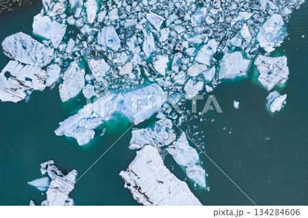 Aerial view of a glacial lagoon in Iceland featuring floating icebergs of various sizes and textures in turquoise water, showcasing icy landscapes. Aerial view of a glacial lagoon in Iceland featuring floating icebergs of various sizes and textures in turquoise water, showcasing icy landscapes. 134284606