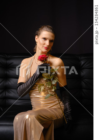Woman holding a rose while sitting on a couch in a studio setting during a photoshoot 134284861