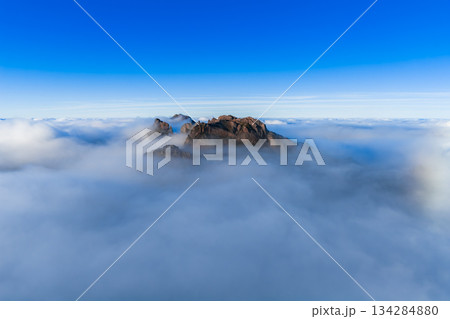Jagged Pico do Arieiro on Madeira Island, Portugal, rises through a cloud inversion at sunrise. Crisp light and minimal composition isolate the craggy ridge. 134284880