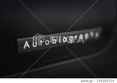 A close up shows the Autobiography badge on a glossy dark panel in a luxury car workshop. Soft lighting and shallow depth of field highlight premium branding. A close up shows the Autobiography badge on a glossy dark panel in a luxury car workshop. Soft lighting and shallow depth of field highlight premium branding. 134285314