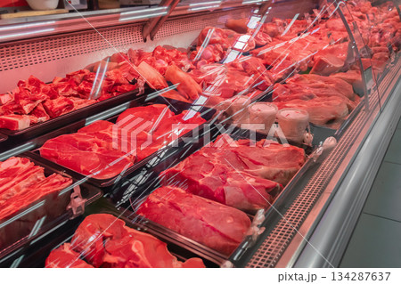 Fresh red meat display at a shop featuring beef and pork cuts in a well-organized showcase for customers during daylight hours. Chilled fresh meat, beef or pork fillet on a display case red lighting Fresh red meat display at a shop featuring beef and pork cuts in a well-organized showcase for customers during daylight hours. Chilled fresh meat, beef or pork fillet on a display case red lighting 134287637