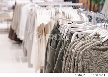 Clothes hang on display racks in a retail store during the day for shoppers to browse and choose items for purchase. High quality photo Clothes hang on display racks in a retail store during the day for shoppers to browse and choose items for purchase. High quality photo 134287641
