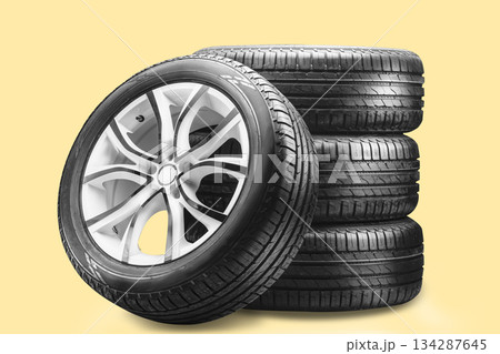 A set of summer wheels on a yellow background. A stack of summer tires with sleek alloy wheels showcases their sturdy design. These wheels provide enhanced braking and grip for safe driving 134287645