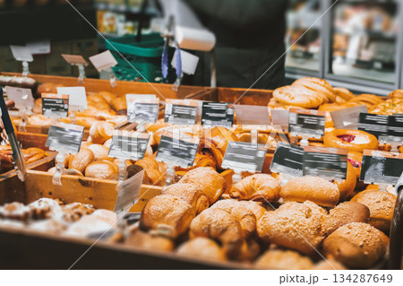 Fresh, delicious pastries - bread and sweet rolls in an assortment on wooden shelves in a modern European supermarket with its own bakery. High quality photo Fresh, delicious pastries - bread and sweet rolls in an assortment on wooden shelves in a modern European supermarket with its own bakery. High quality photo 134287649