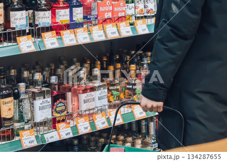 Krasnoyarsk, Russia, 02 02 2025: A male customer chooses strong alcohol in a supermarket window. Alcohol prices, excise tax, and the problem of alcoholism and alcohol dependence. Sales hours. High Krasnoyarsk, Russia, 02 02 2025: A male customer chooses strong alcohol in a supermarket window. Alcohol prices, excise tax, and the problem of alcoholism and alcohol dependence. Sales hours. High 134287655