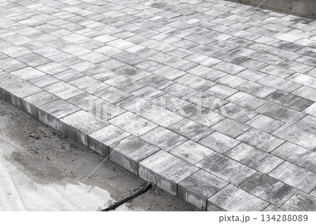 A level outdoor area made of square concrete paver tiles forms a modern walkway 134288089