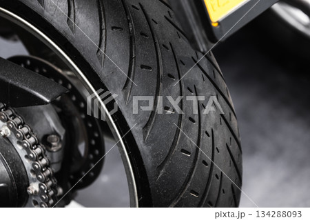 A motorcycle rear wheel, chain, sprocket, and tire, close up view 134288093