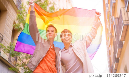 Gay couple celebrating inclusion holding rainbow flag 134289247