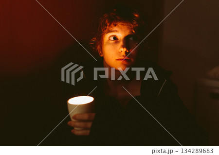 young woman with a candle in a dark room 134289683