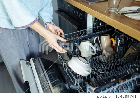 young woman putting dirty dishes into dishwasher at home young woman putting dirty dishes into dishwasher at home 134289741
