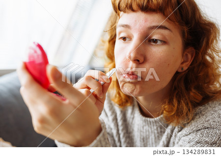 young woman looks at problematic facial skin in mirror 134289831