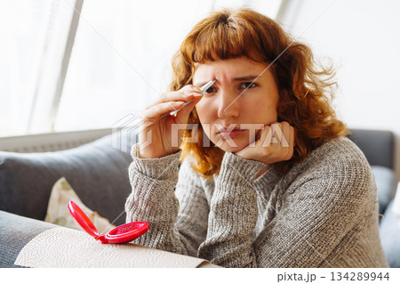 young woman looks at problematic facial skin in mirror 134289944