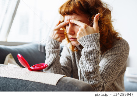 young woman looks at problematic facial skin in mirror young woman looks at problematic facial skin in mirror 134289947