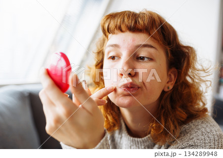young woman looks at problematic facial skin in mirror young woman looks at problematic facial skin in mirror 134289948