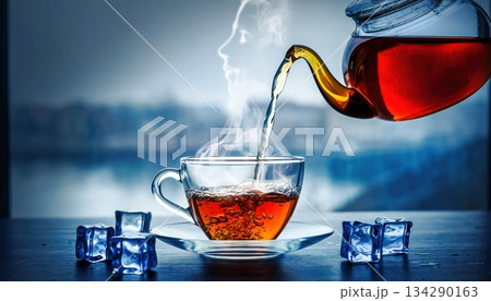 Hot tea being poured into glass cups with steam rising, cozy winter beverage composition representing warmth, hospitality, and comfort in calm light 134290163