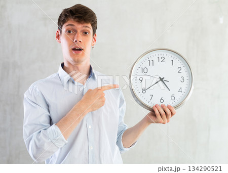 Man with a round big clock in his hands expresses various emotions Man with a round big clock in his hands expresses various emotions 134290521