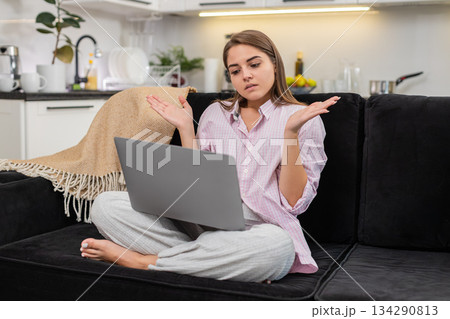 Young woman sees failed task on laptop spreads hands unsure breathes deep plans new approach to work 134290813