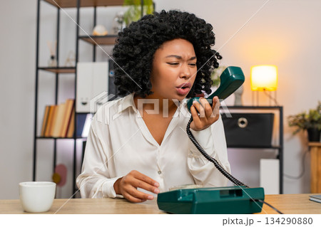 African American businesswoman yells on retro phone waving hand frustrated during angry dispute call 134290880