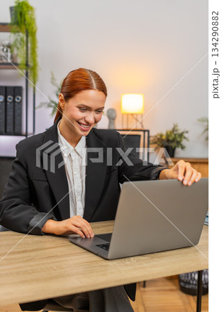 Young businesswoman opens laptop and starts productive work smiling with optimism beginning of day Young businesswoman opens laptop and starts productive work smiling with optimism beginning of day 134290882