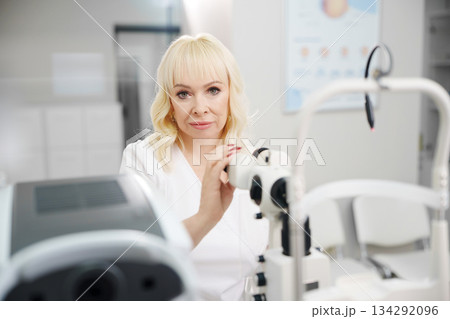 Ophthalmologist examines equipment in a clinic setting Ophthalmologist examines equipment in a clinic setting 134292096