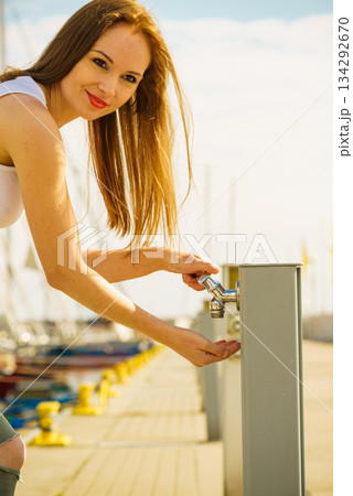 Woman drinking water from tap in marina. Woman drinking water from tap in marina. 134292670
