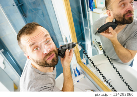 Man shaving trimming his beard Man shaving trimming his beard 134292860