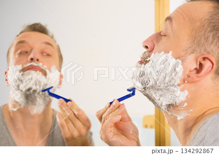 Guy shaving his beard in bathroom Guy shaving his beard in bathroom 134292867