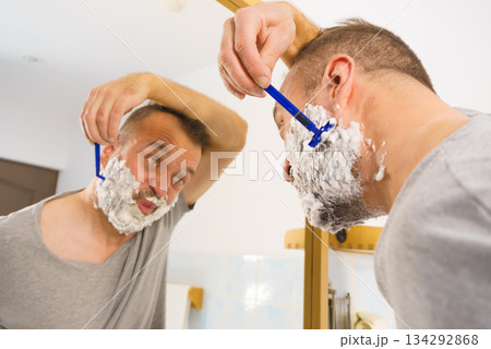 Guy shaving his beard in bathroom 134292868