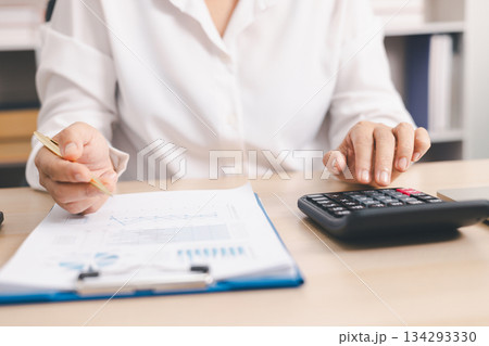 Businessperson using calculator and laptop with financial report on office desk, concept of accounting analysis, budget planning, data management and corporate finance strategy. 134293330