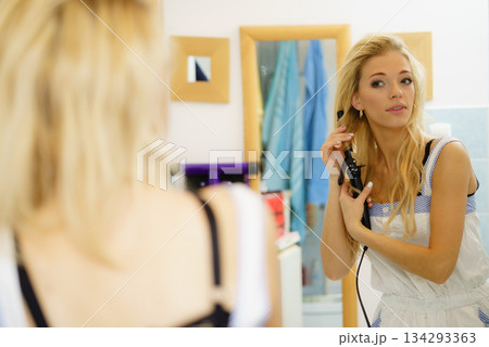 Woman using hair straightener 134293363