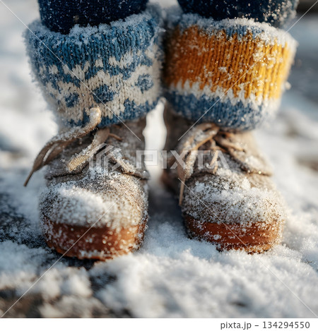 Close-up of children mittens and boots covered in snow while playing outdoors, shallow depth of field, sparkling snow texture Close-up of children mittens and boots covered in snow while playing outdoors, shallow depth of field, sparkling snow texture 134294550