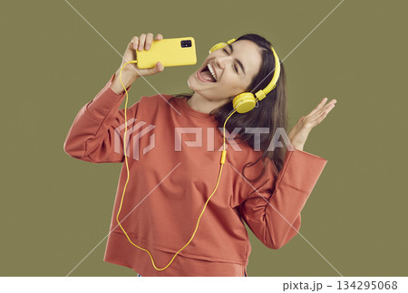 Happy young woman listening music with headphones using mobile phone Happy young woman listening music with headphones using mobile phone 134295068