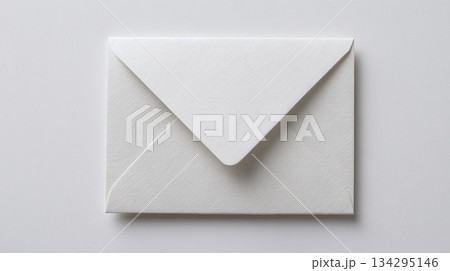 Crisp white envelope lies flat against a light surface, clean lines and shadows create a sense of minimalist elegance, perfect for invitations or business correspondence. 134295146