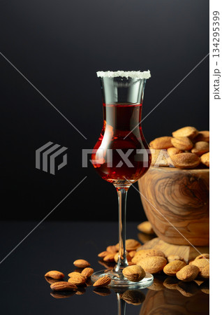 Italian liqueur Amaretto with almonds nuts on a black background. Italian liqueur Amaretto with almonds nuts on a black background. 134295399