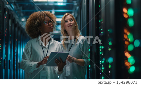 Female IT specialists monitoring server infrastructure in data center 134296073