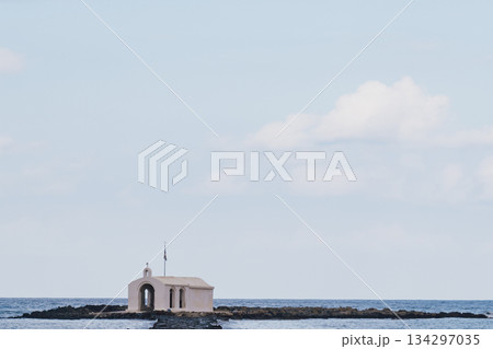 Coastal sentinel: the miniature stone church standing alone against the blue of the Mediterranean 134297035