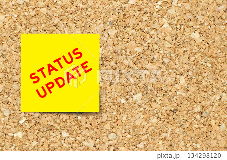 Yellow note paper with word status update on cork board background with copy space 134298120