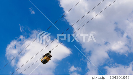 Yellow Cable Car Gondola Against Blue Sky and White Clouds 134301045