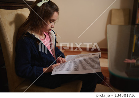 Little Girl Reading a Newspaper While Sitting on a Couch at Home Little Girl Reading a Newspaper While Sitting on a Couch at Home 134301716