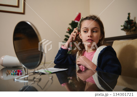 Young Girl Brushing Hair At Desk With Mirror And Christmas Tree In Background 134301721