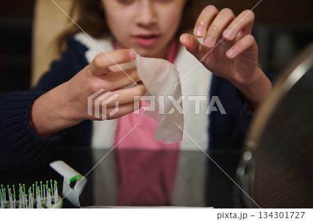 Child Peels Tissue At Table With Toothbrushes And Mirror In Morning Routine Child Peels Tissue At Table With Toothbrushes And Mirror In Morning Routine 134301727