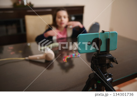 Family Video Setup: Child Talking On Phone While Filming With Tripod At Table 134301736
