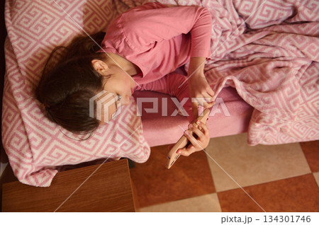 Young Girl Relaxing On Pink Couch With Phone, Cozy Blanket, Home Comfort 134301746