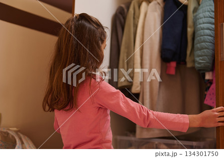Girl In Pink Shirt Opens Wardrobe Full Of Coats And Jackets At Home 134301750